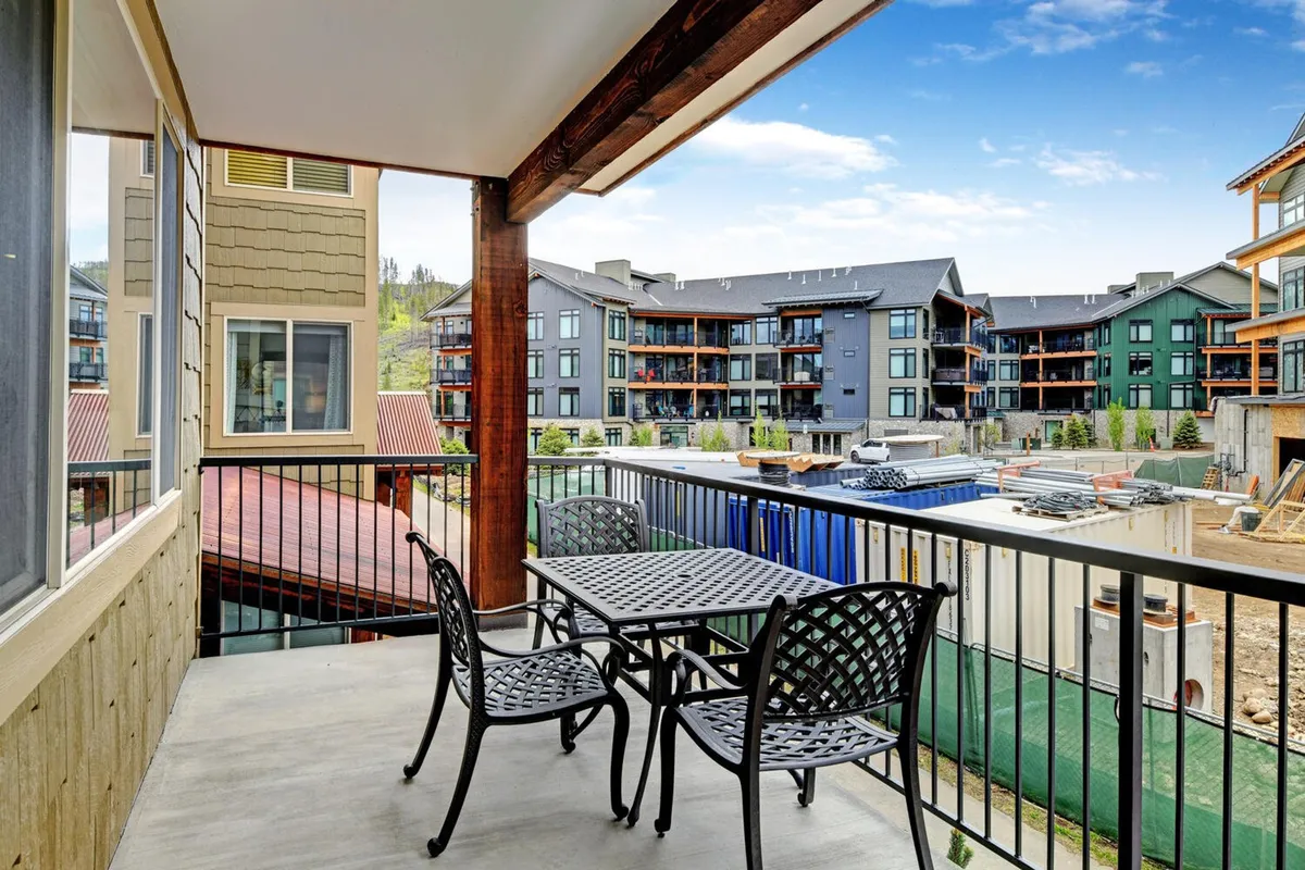 A balcony scene with cozy seating overlooking surrounding buildings and an open outdoor view. The atmosphere is casual and comfortable, suggesting a spot to relax with your pet while taking in the sights and sounds of the mountain community.