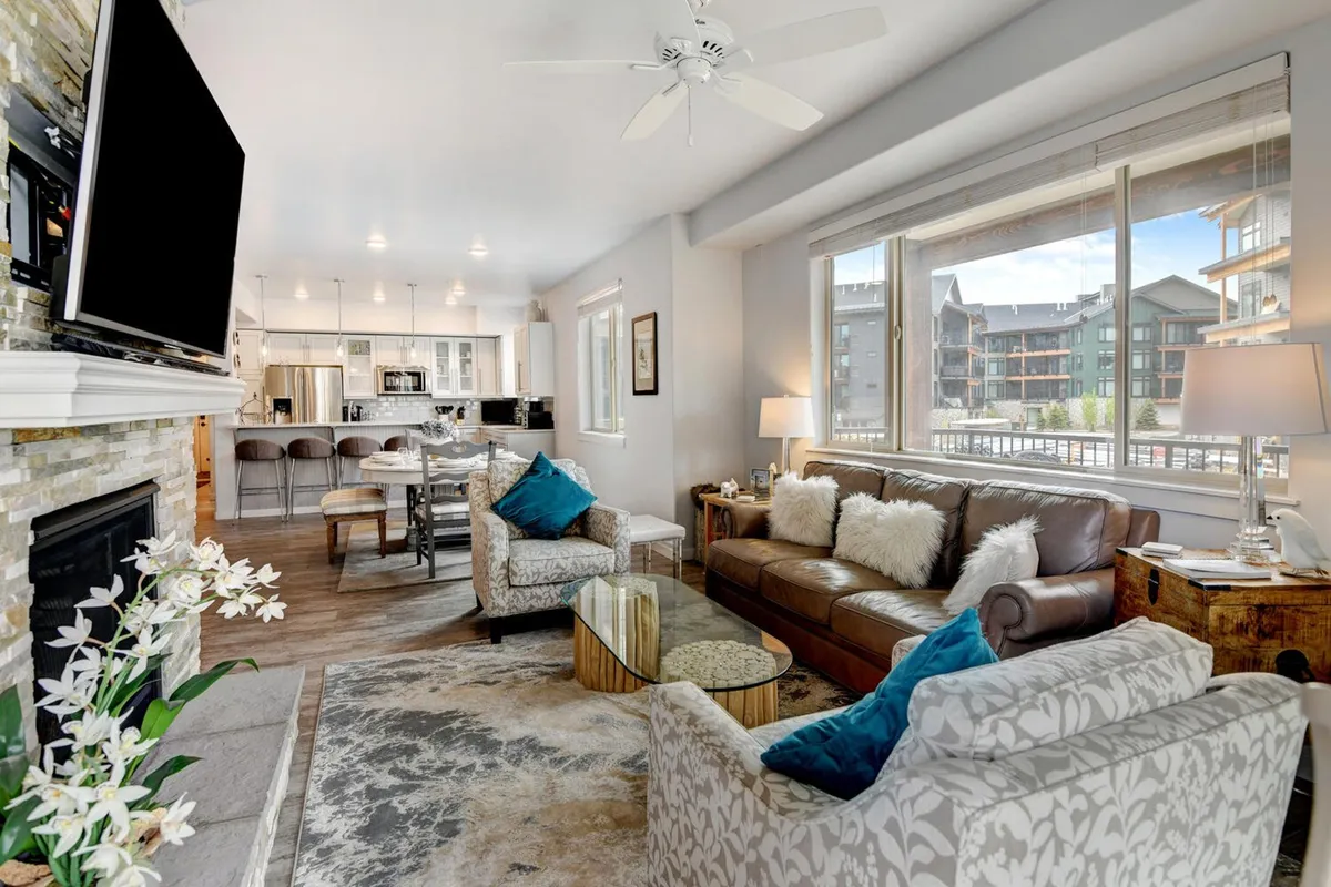 A cozy lounge area inside the clubhouse, anchored by a large television and a warm fireplace, with plush sofas and a window view. The space is ideal for movie nights, group gatherings, or simply relaxing in comfort.