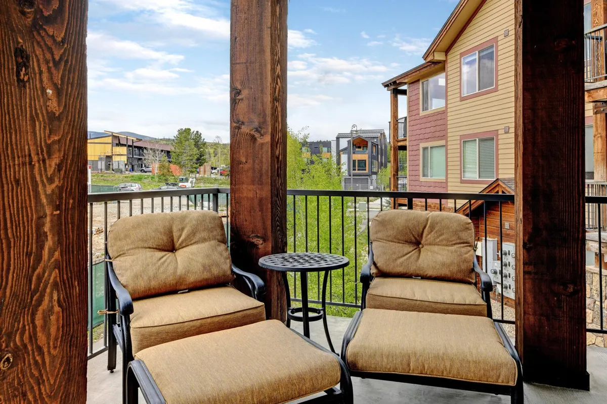 This exterior scene features comfortable lounge chairs and a small round table set on a patio surrounded by lush greenery. Wooden pillars frame the outdoor area, creating an inviting space ideal for relaxing, socializing, or enjoying the sunrise or sunset. The tranquil ambiance suggests a direct connection to nature and outdoor recreation.