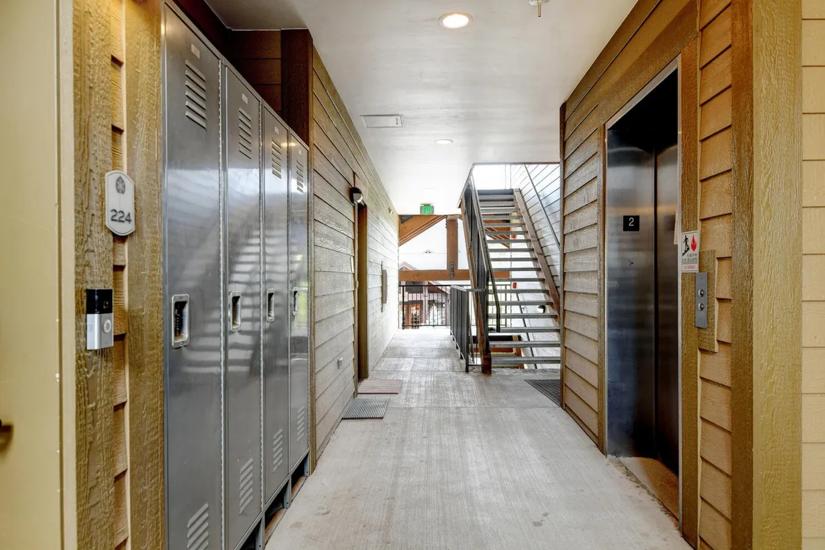 This space shows metal lockers, an elevator, and a staircase, signifying the practical side of adventure—storing equipment, coming back from the slopes, or heading out to explore. The image feels dynamic and purposeful, suited to active, seasonal lifestyles.