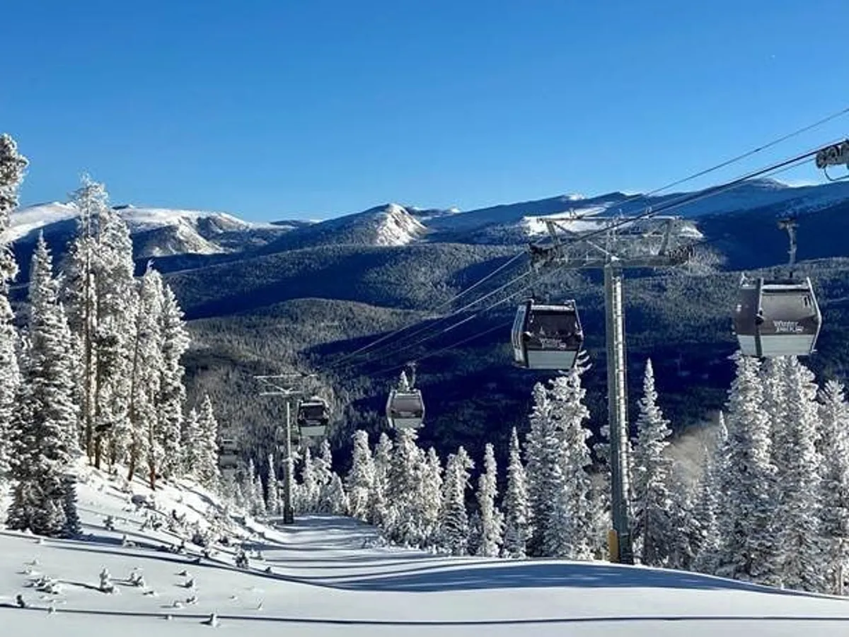 A panoramic view of snow-covered mountains with ski lift gondolas gliding between frosted trees. The scene offers a sense of awe and tranquility, inviting guests to imagine themselves experiencing the majestic landscape firsthand, whether skiing, snowboarding, or simply taking in the views.