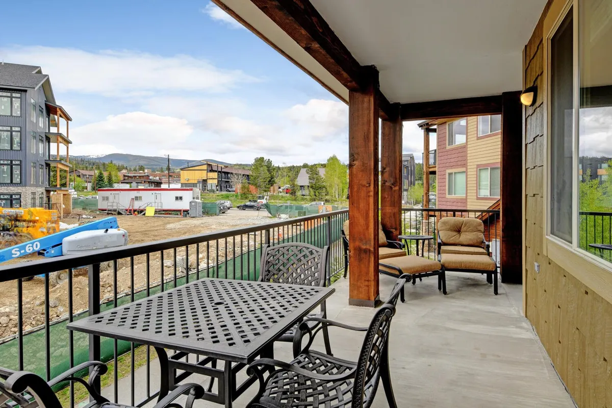 A welcoming outdoor balcony featuring comfortable seating, a dining table, and sweeping mountain views in the distance. The area is well-appointed for relaxation or social gatherings, with the natural scenery providing a resort-like atmosphere.