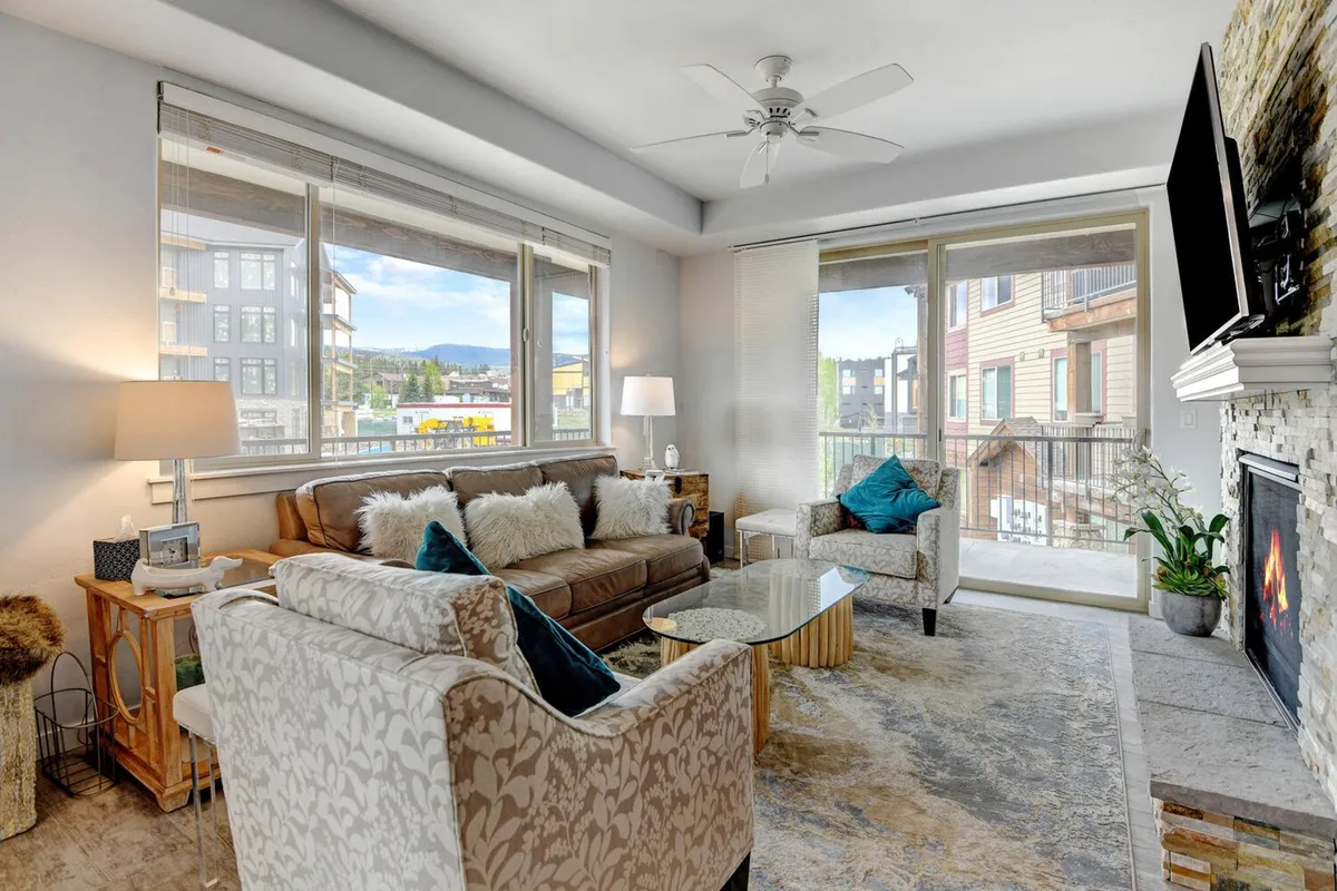 A cozy living room setting featuring a stylish sofa with plush pillows, a glowing fireplace, large windows letting in natural light, and a chic coffee table. The atmosphere is one of relaxation, comfort, and togetherness—ideal for unwinding after an adventurous day.