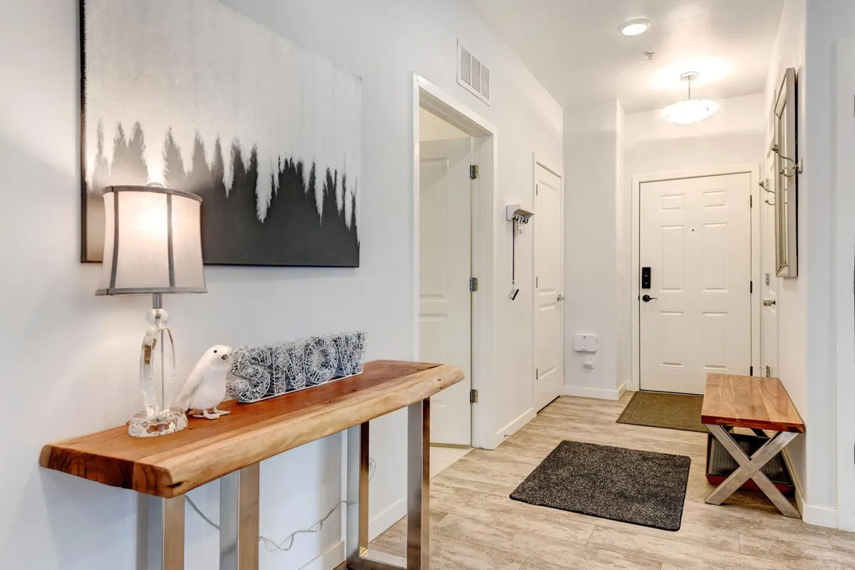 This image captures an inviting entryway featuring a console table, lamp, artwork, and a bench—elements that evoke the experience of arriving at or departing for seasonal adventures in Winter Park. The welcoming decor hints at a cozy and hospitable atmosphere, which aligns with the section's focus on year-round enjoyment and exploration.